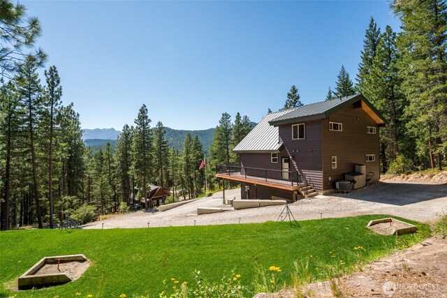 55 Wrangler Ln, Leavenworth, WA 98826 - rear view of house with a deck with mountain view, a yard, a view of trees, and metal roof