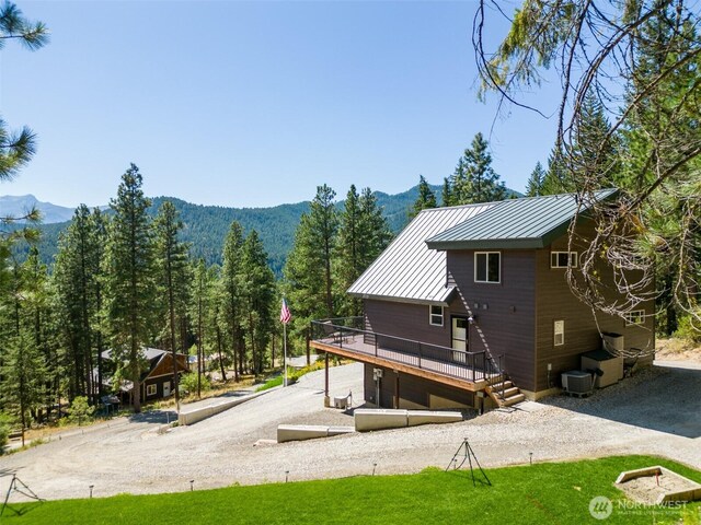 55 Wrangler Ln, Leavenworth, WA 98826 - back of property featuring a deck with mountain view, metal roof, central air condition unit, a standing seam roof, and driveway