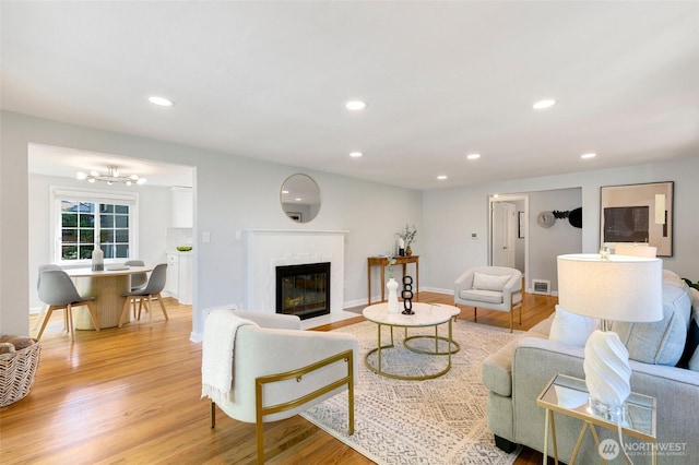 1703 NE 91st St, Seattle, WA 98115 - living room featuring light wood-style flooring, a fireplace with flush hearth, recessed lighting, and a chandelier