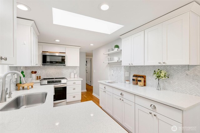 1703 NE 91st St, Seattle, WA 98115 - kitchen featuring stainless steel appliances, a skylight, open shelves, backsplash, and white cabinetry