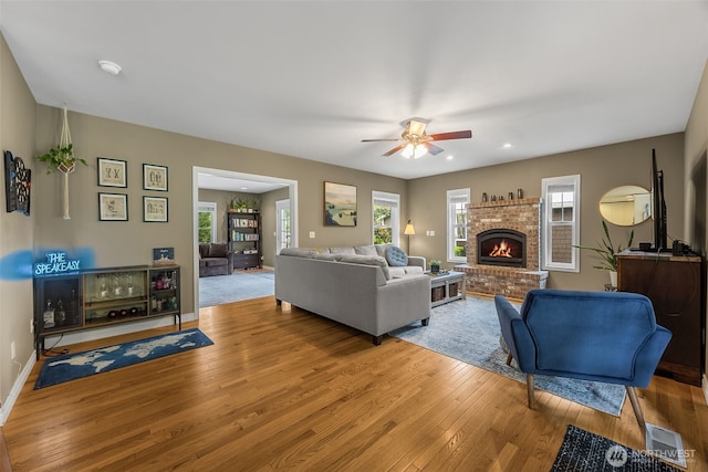 675 Bowker St SE, Lacey, WA 98503 - living room featuring hardwood / wood-style floors, a ceiling fan, a brick fireplace, and baseboards