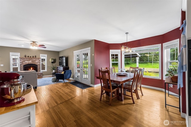 675 Bowker St SE, Lacey, WA 98503 - dining space with light wood-type flooring, a brick fireplace, baseboards, french doors, and plenty of natural light