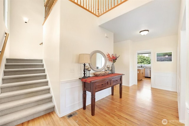 1048 Cassius Ct, Camano Island, WA 98282 - staircase with wood finished floors, a wainscoted wall, and a decorative wall