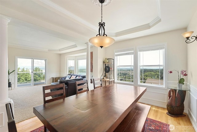 1048 Cassius Ct, Camano Island, WA 98282 - dining area with decorative columns, a tray ceiling, a wainscoted wall, light wood-style flooring, and ornamental molding