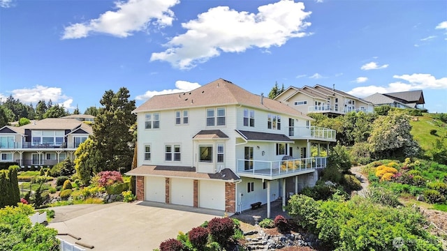 1048 Cassius Ct, Camano Island, WA 98282 - rear view of house with a balcony, concrete driveway, an attached garage, brick siding, and roof with shingles