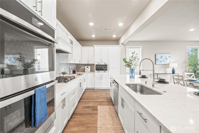 25701 204th Pl SE, Covington, WA 98042 - kitchen with stainless steel appliances, a sink, custom exhaust hood, recessed lighting, and white cabinets