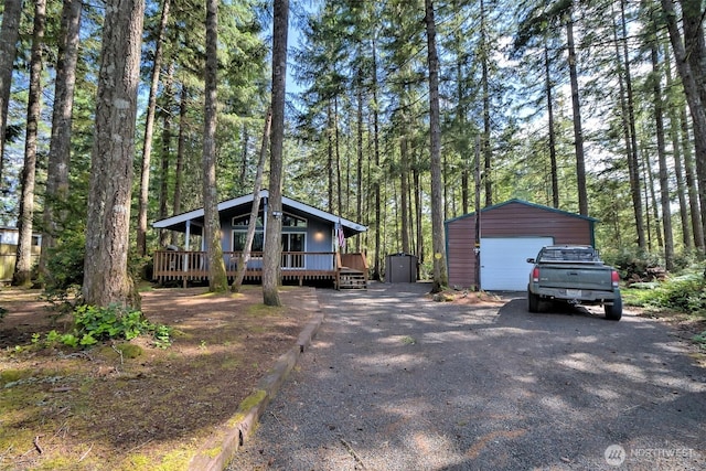 201 E Sleaford Rd, Shelton, WA 98584 - view of front of property featuring a detached garage, an outbuilding, driveway, a wooden deck, and a wooded view