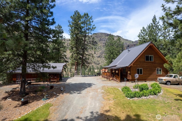 21 Oakes Dr, Tonasket, WA 98855 - view of property exterior with log siding, a mountain view, a metal roof, a porch, and gravel driveway