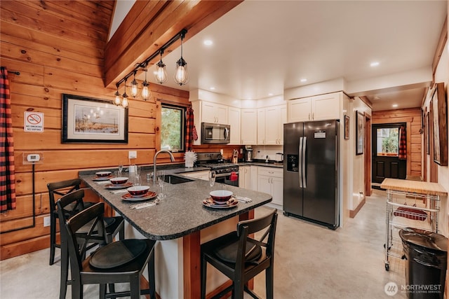 15033 Welcome Rd, Glacier, WA 98244 - kitchen with appliances with stainless steel finishes, a sink, wood walls, white cabinetry, and a breakfast bar