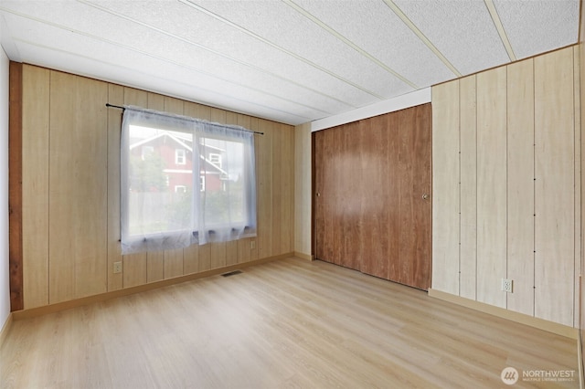 1405 226th St NW, Silvana, WA 98287 - unfurnished bedroom with wood finished floors, wood walls, a closet, and a textured ceiling