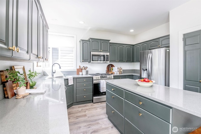 7117 Axis St SE, Lacey, WA 98513 - kitchen with appliances with stainless steel finishes, gray cabinetry, light stone counters, light wood-type flooring, and recessed lighting
