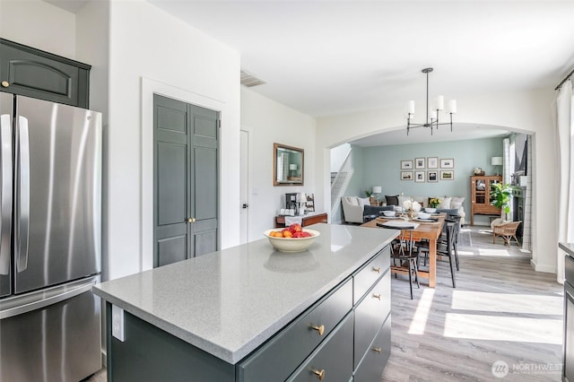 7117 Axis St SE, Lacey, WA 98513 - kitchen featuring freestanding refrigerator, arched walkways, light wood finished floors, a center island, and open floor plan
