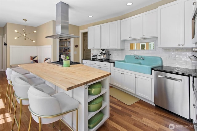 301 Weaver Rd NW, Bainbridge Island, WA 98110 - kitchen with stainless steel appliances, island range hood, a sink, wooden counters, and backsplash