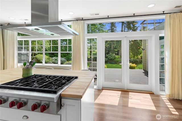 301 Weaver Rd NW, Bainbridge Island, WA 98110 - kitchen with island range hood, stainless steel gas stovetop, wood counters, and light wood-style floors