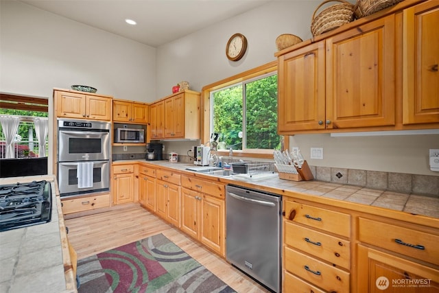 23405 Jordan Rd, Arlington, WA 98223 - kitchen featuring appliances with stainless steel finishes, a sink, light wood-style flooring, and tile counters