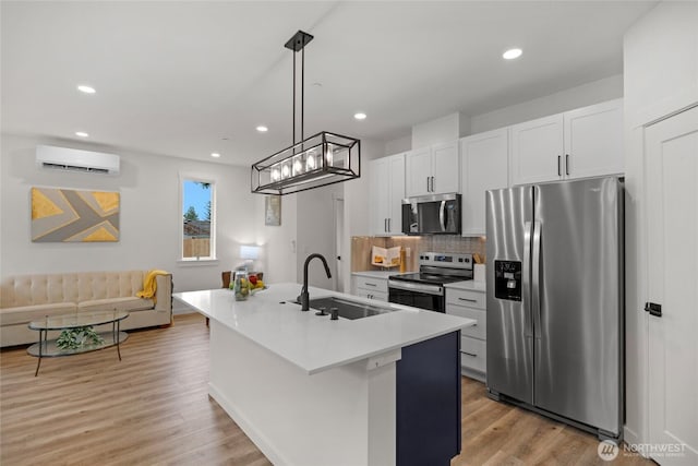 2617 Spruce Rd Unit A, Lake Stevens, WA 98258 - kitchen with appliances with stainless steel finishes, a sink, a wall mounted AC, light wood-style flooring, and a kitchen island with sink