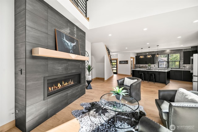 141 Pebble Beach Dr, Cle Elum, WA 98922 - living room featuring light wood-style flooring, a tiled fireplace, recessed lighting, baseboards, and stairway