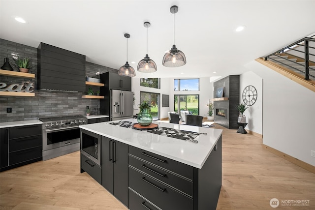 141 Pebble Beach Dr, Cle Elum, WA 98922 - kitchen with open shelves, dark cabinetry, high quality appliances, wall chimney exhaust hood, and backsplash