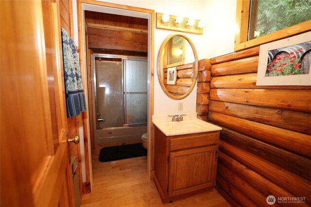 215 Marine Dr, Blakely Island, WA 98222 - full bathroom featuring vanity, toilet, bath / shower combo with glass door, wood finished floors, and log walls
