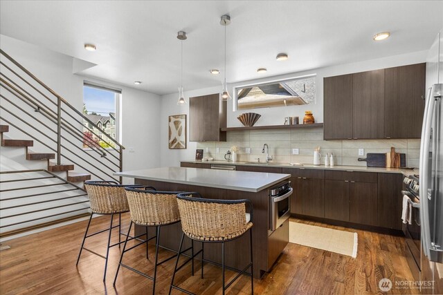 8838 Interlake Ave N, Seattle, WA 98103 - kitchen featuring dark brown cabinets, a kitchen bar, a sink, decorative backsplash, and appliances with stainless steel finishes