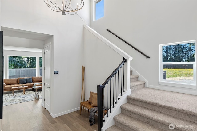 11210 79th Avenue Ct SW, Lakewood, WA 98498 - stairs featuring healthy amount of natural light, a chandelier, wood finished floors, a towering ceiling, and baseboards