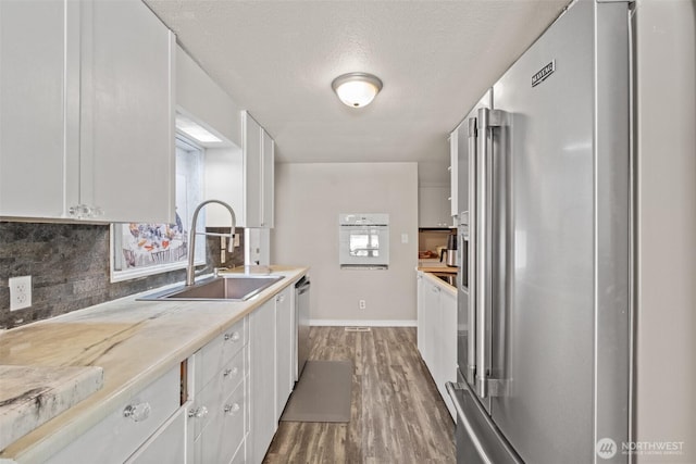 7938 E Leavenworth Rd, Leavenworth, WA 98826 - kitchen with appliances with stainless steel finishes, a sink, white cabinetry, decorative backsplash, and light wood-style floors