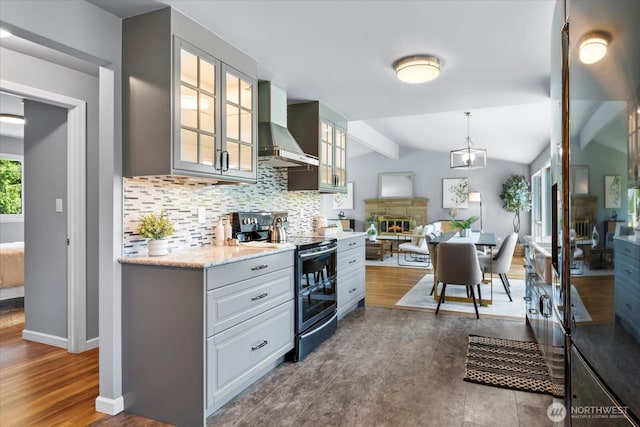 22606 87th Ave W, Edmonds, WA 98026 - kitchen featuring wall chimney range hood, range with two ovens, backsplash, a fireplace, and glass insert cabinets