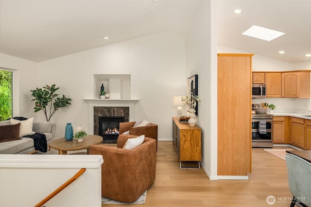 3816 NE 110th St, Seattle, WA 98125 - living room featuring vaulted ceiling, a fireplace, light wood-style flooring, a skylight, and recessed lighting