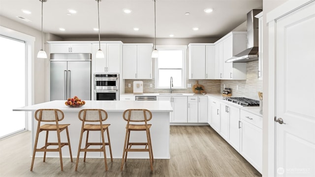 13473 NE 105th Ct Unit 12, Kirkland, WA 98033 - kitchen featuring appliances with stainless steel finishes, wall chimney exhaust hood, a sink, a kitchen island, and light wood-style floors