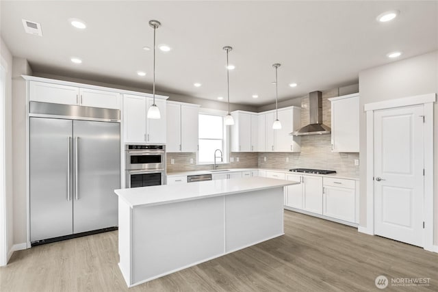 13473 NE 105th Ct Unit 12, Kirkland, WA 98033 - kitchen with appliances with stainless steel finishes, wall chimney exhaust hood, light wood finished floors, a kitchen island, and light countertops