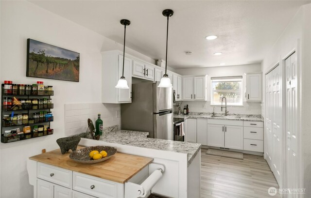 1123 Mather Dr, Moses Lake, WA 98837 - kitchen featuring a sink, freestanding refrigerator, tasteful backsplash, a peninsula, and white cabinetry