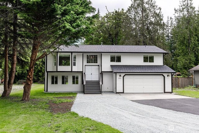 8302 319th St NW, Stanwood, WA 98292 - raised ranch with a garage, driveway, and roof with shingles