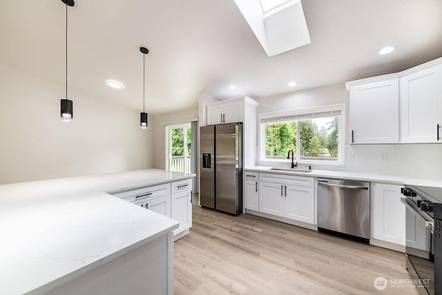 8302 319th St NW, Stanwood, WA 98292 - kitchen featuring appliances with stainless steel finishes, a sink, a skylight, white cabinets, and recessed lighting