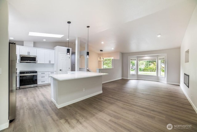 8302 319th St NW, Stanwood, WA 98292 - kitchen featuring appliances with stainless steel finishes, white cabinets, open floor plan, light wood-style floors, and lofted ceiling