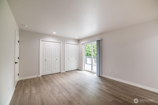 8302 319th St NW, Stanwood, WA 98292 - unfurnished bedroom featuring wood finished floors, access to outside, baseboards, two closets, and recessed lighting