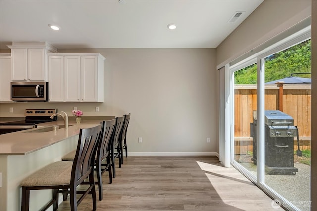 8605 E Gilman Ave, Arlington, WA 98223 - kitchen with appliances with stainless steel finishes, a kitchen breakfast bar, white cabinets, light wood-style floors, and recessed lighting