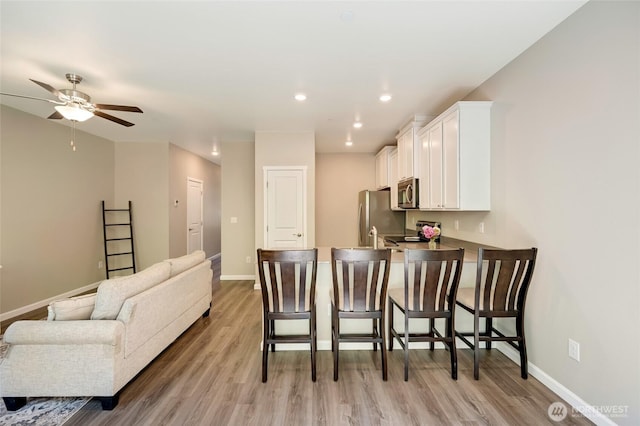 8605 E Gilman Ave, Arlington, WA 98223 - kitchen featuring appliances with stainless steel finishes, a breakfast bar area, white cabinetry, light wood finished floors, and recessed lighting