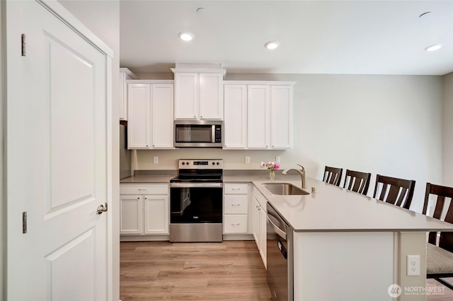 8605 E Gilman Ave, Arlington, WA 98223 - kitchen featuring stainless steel appliances, a breakfast bar area, a peninsula, white cabinets, and light wood-type flooring