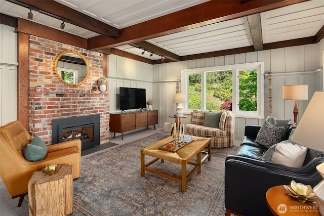 14830 Glen Acres Rd SW, Vashon, WA 98070 - carpeted living area with rail lighting, beamed ceiling, a fireplace, and a decorative wall