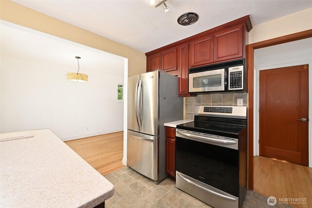 4245 Williams Ave W, Seattle, WA 98199 - kitchen featuring appliances with stainless steel finishes, light countertops, tasteful backsplash, light wood-style floors, and hanging light fixtures