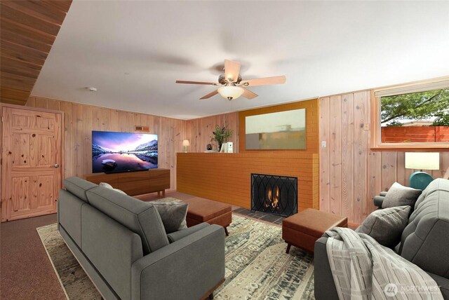 4245 Williams Ave W, Seattle, WA 98199 - carpeted living room with wooden walls, a fireplace with flush hearth, and ceiling fan