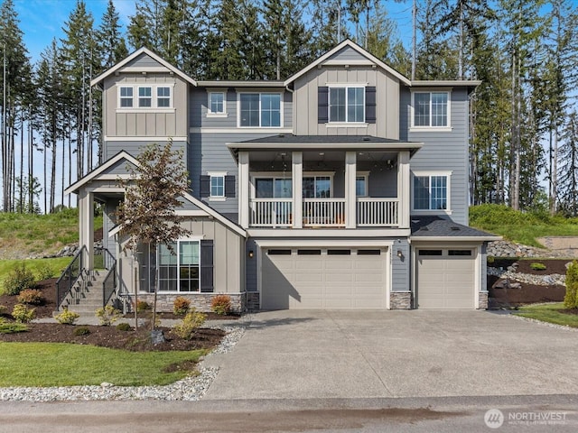 14505 117th St NE, Lake Stevens, WA 98258 - view of front facade featuring board and batten siding, a garage, stone siding, and a balcony