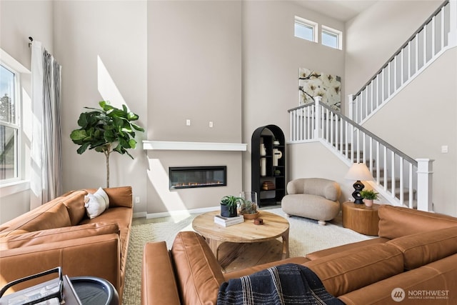 769 SE 12th Pl Unit 29, North Bend, WA 98045 - living room featuring a high ceiling, stairs, a glass covered fireplace, and baseboards