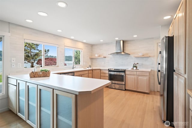 11521 E State Route 106, Union, WA 98592 - kitchen with appliances with stainless steel finishes, wall chimney range hood, a peninsula, a sink, and light wood-style floors