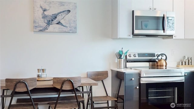890 Magellan Ave NE Unit 2, Ocean Shores, WA 98569 - kitchen featuring stainless steel appliances, white cabinetry, light countertops, and breakfast area