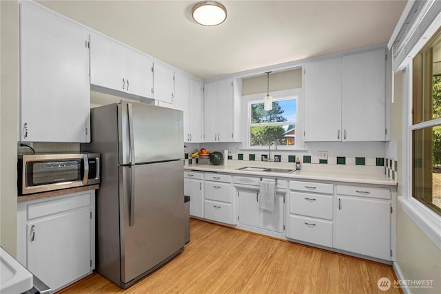 4211 108th Ave E, Edgewood, WA 98372 - kitchen with stainless steel appliances, light countertops, light wood finished floors, white cabinets, and pendant lighting