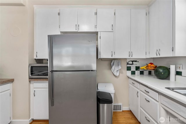 4211 108th Ave E, Edgewood, WA 98372 - kitchen featuring appliances with stainless steel finishes, light wood-type flooring, light countertops, and white cabinets