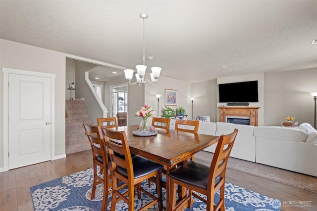301 K St NE, Quincy, WA 98848 - dining room featuring stairway, wood finished floors, a chandelier, and a glass covered fireplace