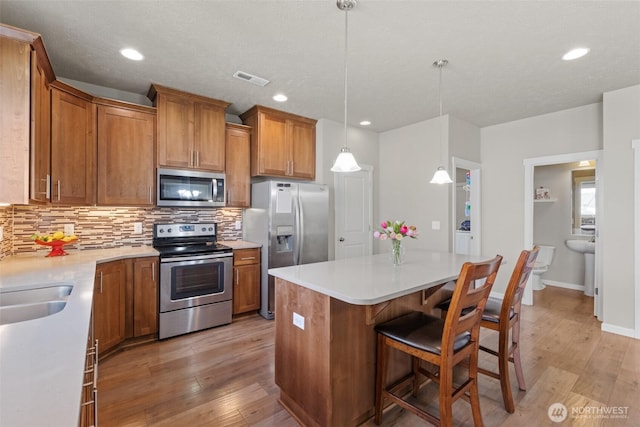 301 K St NE, Quincy, WA 98848 - kitchen featuring stainless steel appliances, brown cabinetry, backsplash, light wood-style floors, and recessed lighting