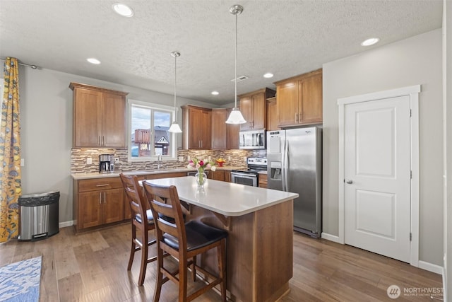 301 K St NE, Quincy, WA 98848 - kitchen featuring stainless steel appliances, a sink, backsplash, brown cabinetry, and a textured ceiling